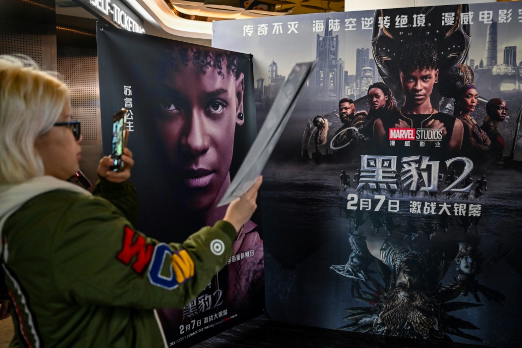 شابة تلتقط صورة لملصق فيلم "بلاك بانثر: واكاندا فوريفر" في إحدى دور السينما في شنغهاي بتاريخ السادس من شباط/فبراير 2023 (ا ف ب)
