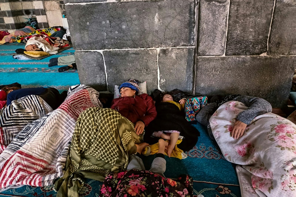    عائلات تركية تنام إلى جانب العائلات السورية على السجادة الفيروزية للمسجد الكبير في ديار بكر (ا ف ب)