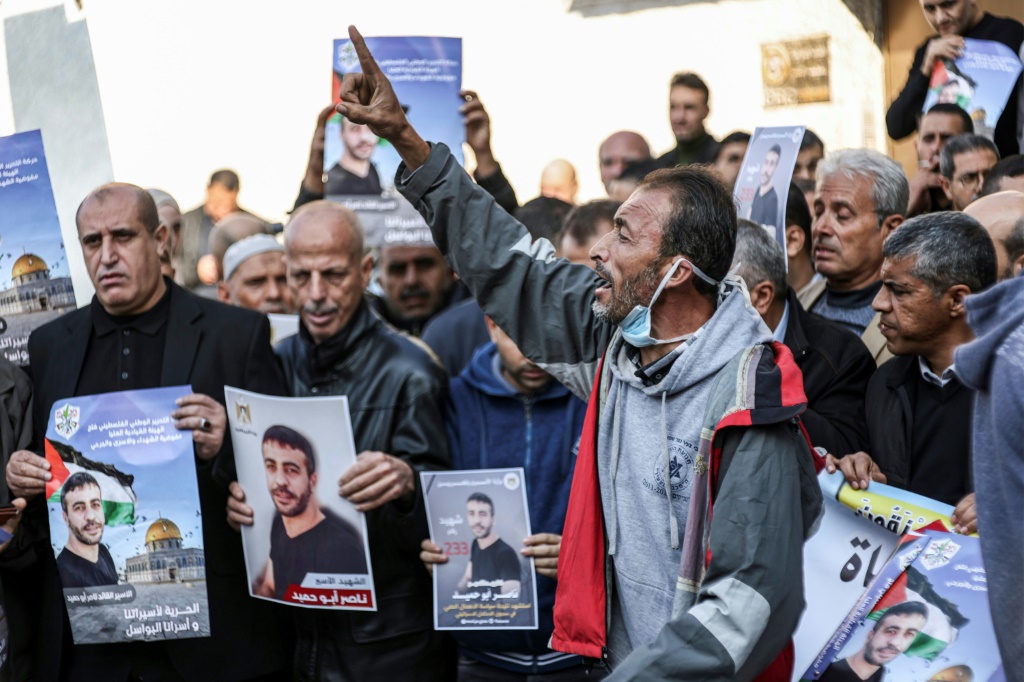معتصمون فلسطينيون يحملون صور الاسير ناصر ابو حميد الذي توفى في السجون الاسرائيلية امام مقر اللجنة الدولية للصليب الاحمر في غزة في العشرين من كانون الاول/ديمسبر 2022 (ا ف ب)