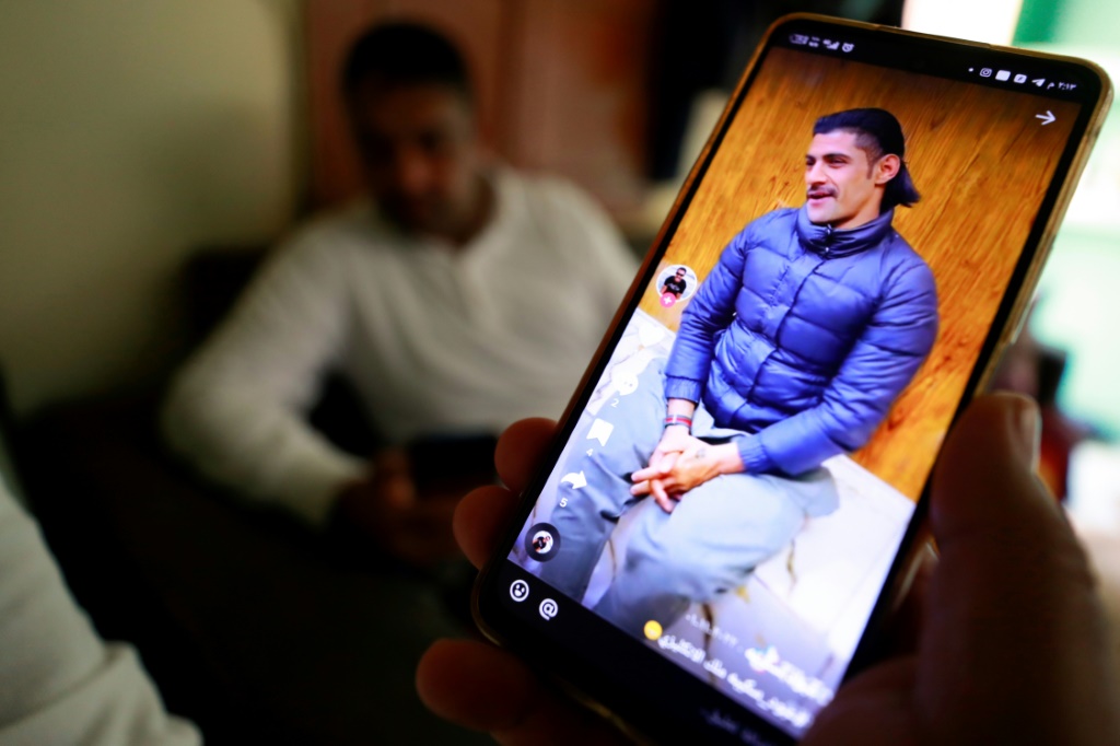    رجل عراقي ينظر عبر هاتفه الى صانع محتوى عراقي معروف على "تيك توك" عبود سكيبة في 12 شباط/فبراير 2023 (أ ف ب)