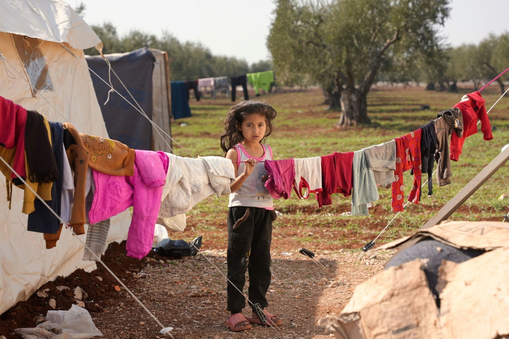     فتاة سورية قرب خيمة وعلى بعد أمتار من منزلها المدمر بسبب الزلزال في جنديرس في سوريا في 13 شباط/فبراير 2023 (ا ف ب)