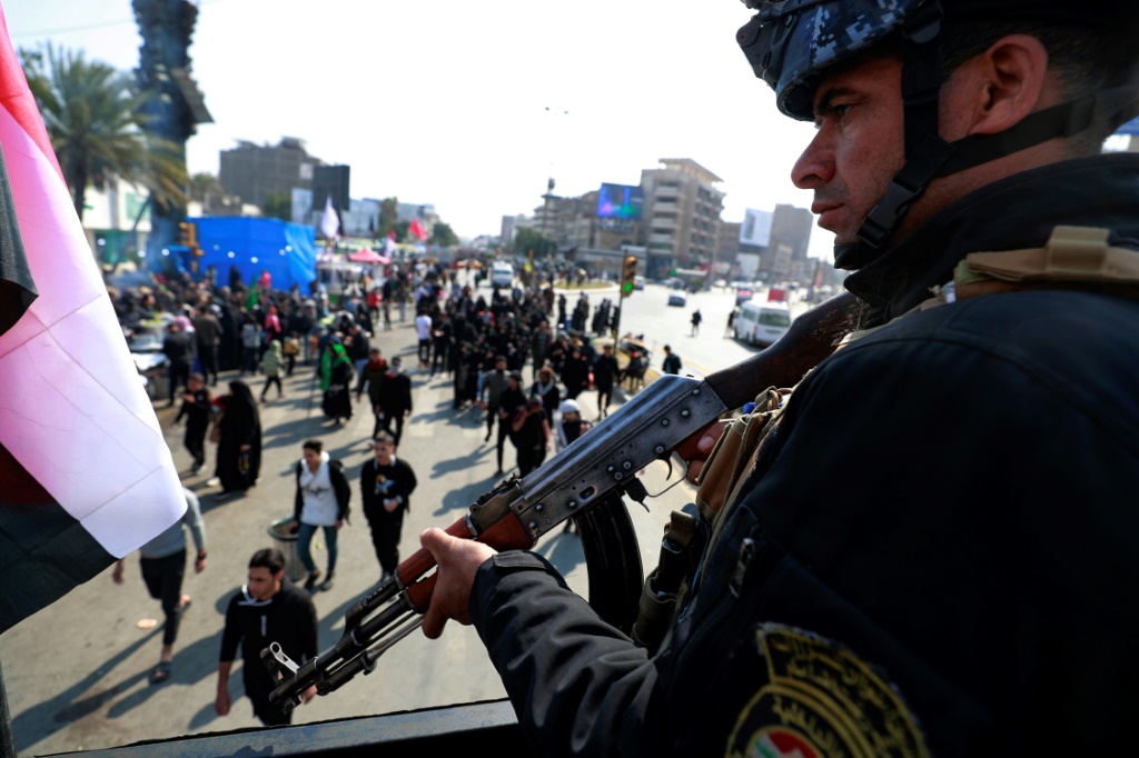 عنصر من القوات الأمنية يقوم بحراسة زوار متجهين إلى مرقد الإمام الكاظم في بغداد في 15 شباط/فبراير 2023 (ا ف ب)