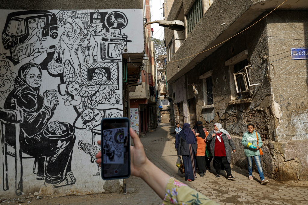 صورة التقطت في 11 كانون الثاني/يناير 2023 لامرأة تصوّر بهاتفها النقّال خلال جولة سياحية في حي الخليفة في القاهرة القديمة (ا ف ب)