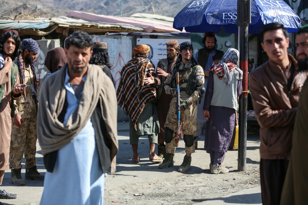 رجال أفغان وعناصر أمن من طالبان يقفون حراسة على طريق بالقرب من معبر تورخام الحدودي مع باكستان بعد إطلاق نار يوم الاثنين. (أ ف ب)