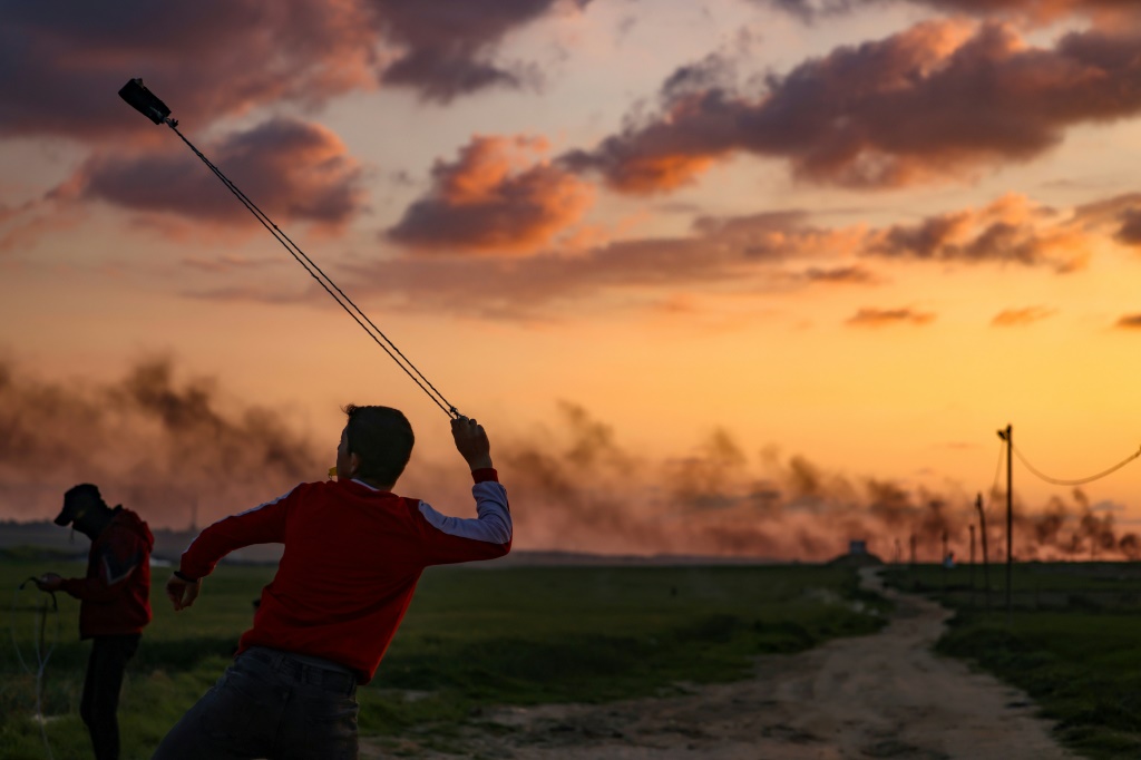 شبان فلسطينيون يرشقون الحجارة باتجاه القوات الإسرائيلية أثناء احتجاجهم بالقرب من الحدود بين إسرائيل وغزة شرق مخيم جباليا للاجئين في 24 شباط/فبراير 2023 (أ ف ب)