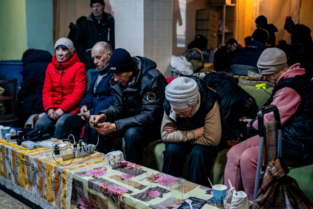 أوكرانيون يتحقّقون من هواتفهم في مركز للمساعدة الإنسانية في باخموت، في 27 شباط/فبراير 2023 وسط الغزو الروسي لأوكرانيا (أ ف ب)