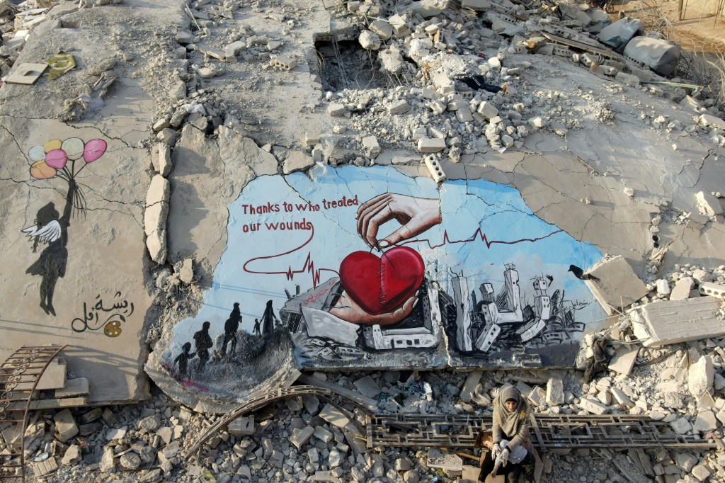 رسم فني على أنقاض مبنى انهار خلال زلزال 6 شباط/فبراير الذي ضرب تركيا وسوريا في بلدة جنديرس التي يسيطر عليها معارضون في شمال سوريا في 22 شباط/شباط 2023 (ا ف ب)