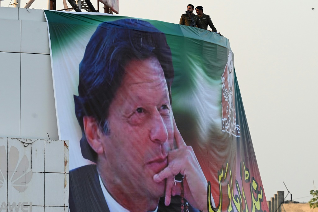 رجال الشرطة يقفون في حراسة فوق صورة لرئيس الوزراء الباكستاني السابق عمران خان خلال مسيرة مناهضة للحكومة في 26 نوفمبر 2022 (أ ف ب)   