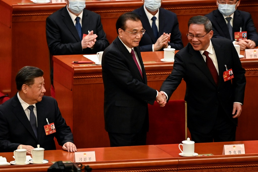رئيس الحكومة الصينية السابق لي كه تشيانغ يصافح رئيس الوزراء المنتخب حديثاً لي تشيانغ بحضور الرئيس الصيني شي جينبينغ خلال جلسة مجلس النواب في بكين في 11 آذار/مارس 2023 (ا ف ب)