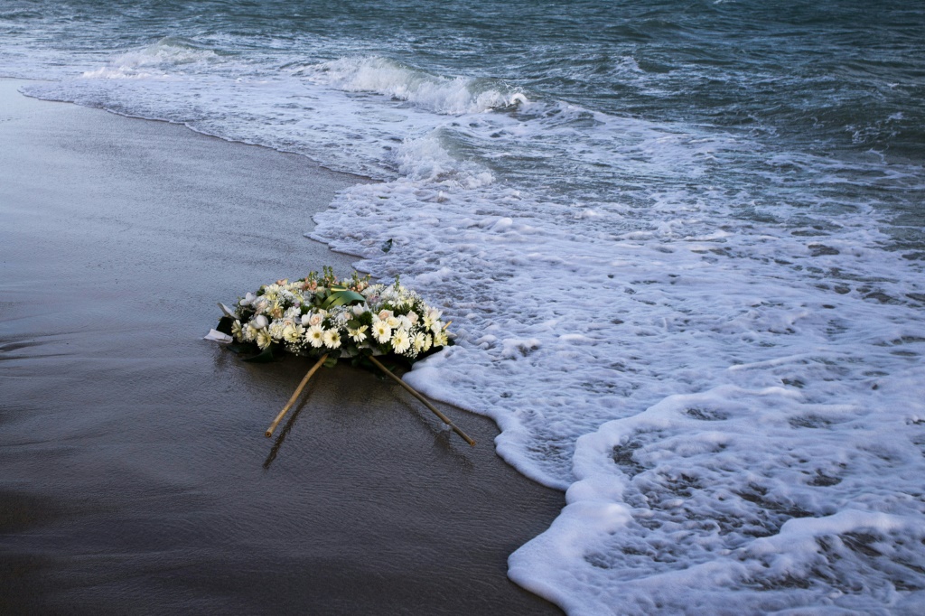إكليل من الزهر يطفو على شاطئ البحر الأبيض المتوسط في موقع غرق سفينة مهاجرين قبالة إيطاليا (ا ف ب)