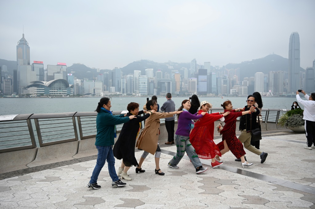 سياح من البر الصيني يرقصون قرب الواجهة البحرية لهونغ كونغ في 13 آذار/مارس 2023 (ا ف ب)