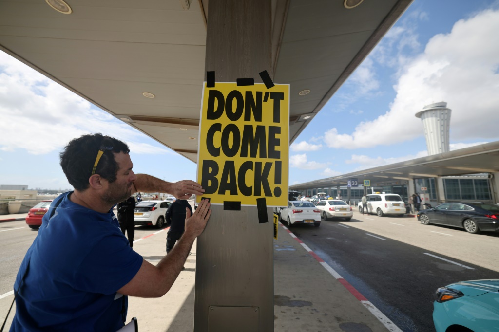 متظاهر إسرائيلي يعلق ملصقا كتب عليه "لا تعود" في رسالة لرئيس الوزراء بنيامين نتانياهو الذي يغادر في زيارة رسمية إلى برلين قرب مطار بن غوريون قرب تل أبيب في 15 آذار/مارس 2023 (ا ف ب)