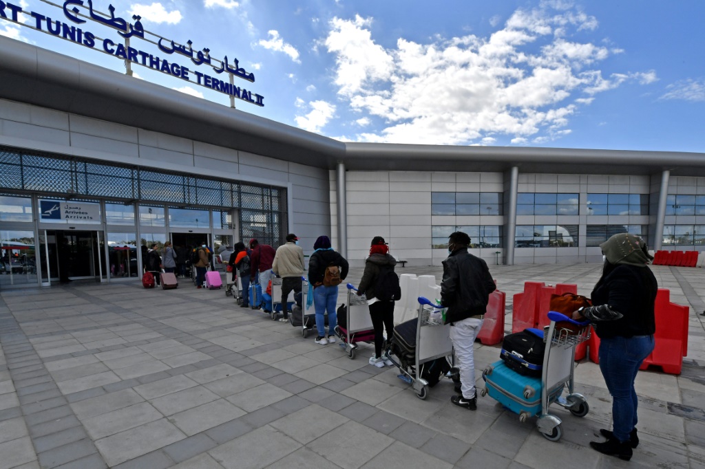     مهاجرون أمام مطار تونس قرطاج الدولي يستعدون للعودة إلى بلدهم الأصلي في السابع من آذار/مارس 2023 (ا ف ب)