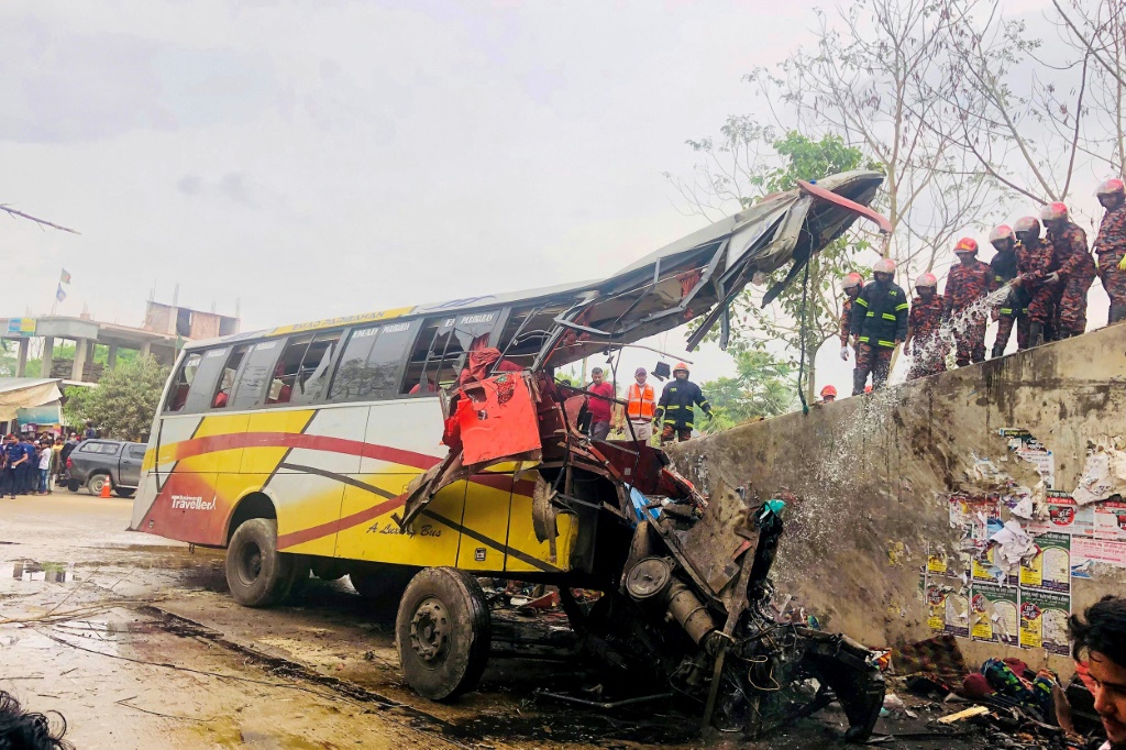رجال إطفاء يحاولون إطفاء النار في حافلة تعرّضت لحادث في ماداريبور في بنغلادش، في 19 آذار/مارس 2023 (ا ف ب)