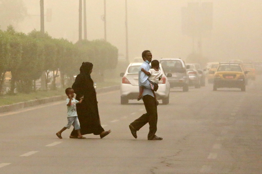 عائلة تعبر الشارع خلال عاصفة ترابية في بغداد في 3 تموز/يوليو 2022 (ا ف ب)