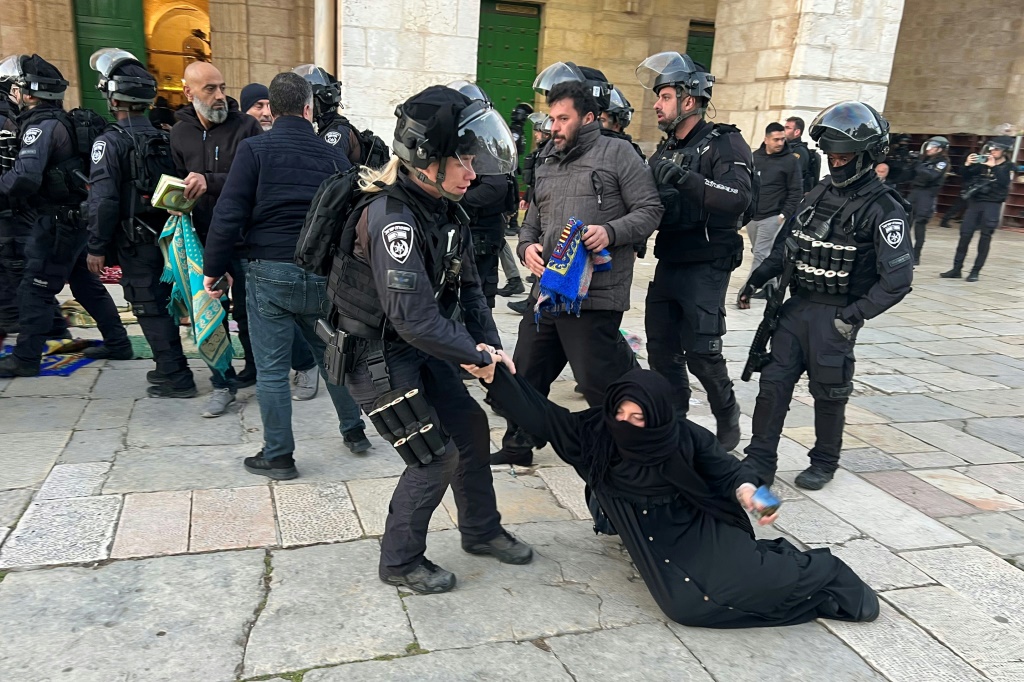 قوات إسرائيلية تسحب سيدة مسلمة تجلس على الأرض في باحات الحرم الشريف في القدس الشرقية المحتلة في الخامس من نيسان/أبريل 2023 وقد شهد المسجد في ساعات الليل مواجهات بين المصلين والقوات الإسرائيلية التي اقتحمته بالعشرات وأوقفت نحو 350 شخصا في صدامات تتزامن مع عيد الفصح اليهودي (ا ف ب)