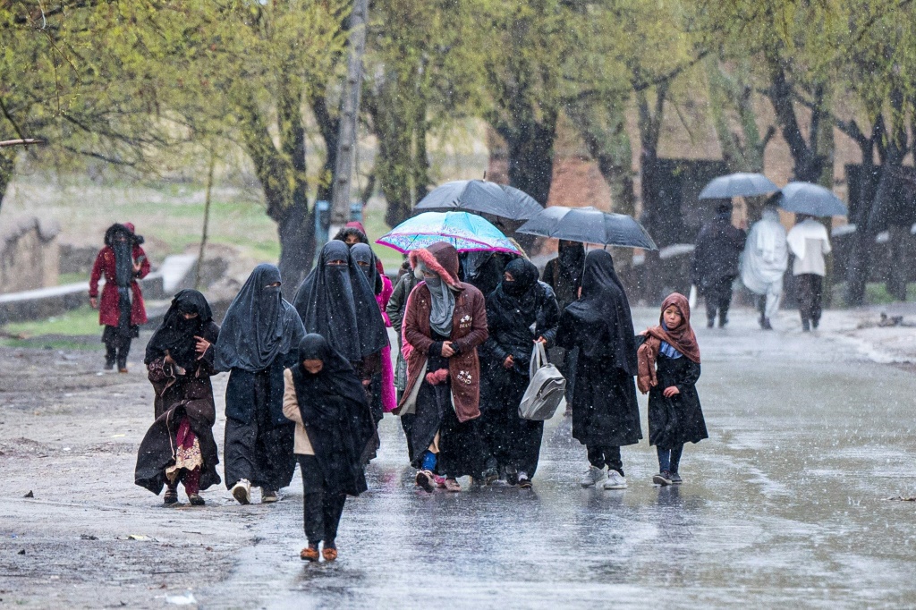     نساء أفغانيات وأطفال يمشون تحت المطار في ضواحي العاصمة الأفغانية كابول في 30 آذار/مارس 2023 (أ ف ب)