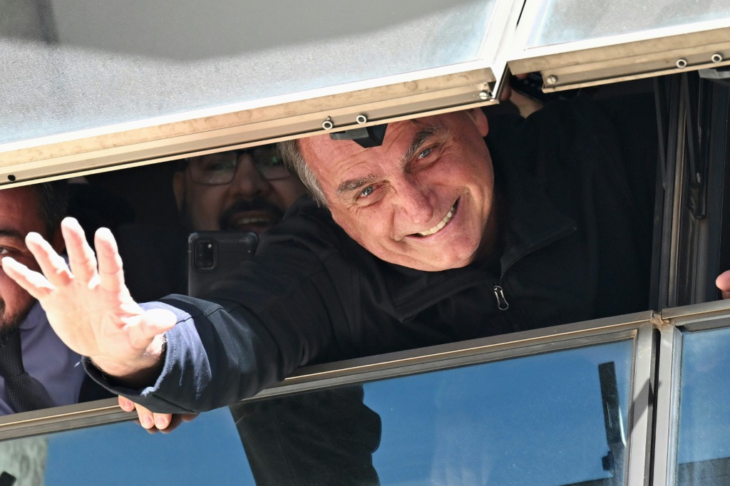 الرئيس البرازيلي السابق جايير بولسونارو يحيي مناصريه من نافذة مبنى الحزب الليبرالي في برازيليا بعد عودته الى البلاد في 30 آذار/مارس 2023. (ا ف ب)