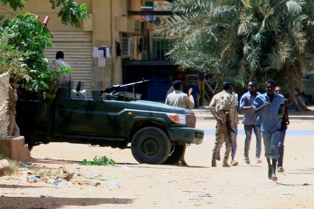 أشخاص يمرون من أمام مركبة عسكرية في الخرطوم (ا ف ب)