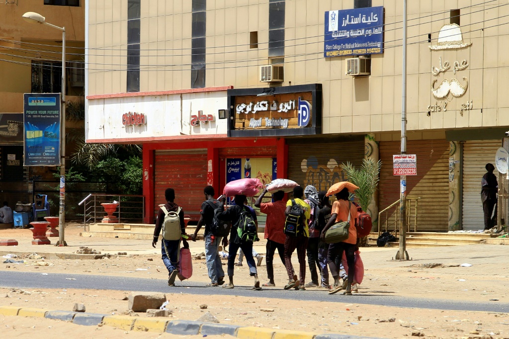 في الخرطوم أشخاص يحملون بعض متاعهم في أحد شوارع الخرطوم في 16 نيسان/أبريل 2023 في اليوم الثاني من القتال بين الجيش وقوات الدعم السريع (ا ف ب)