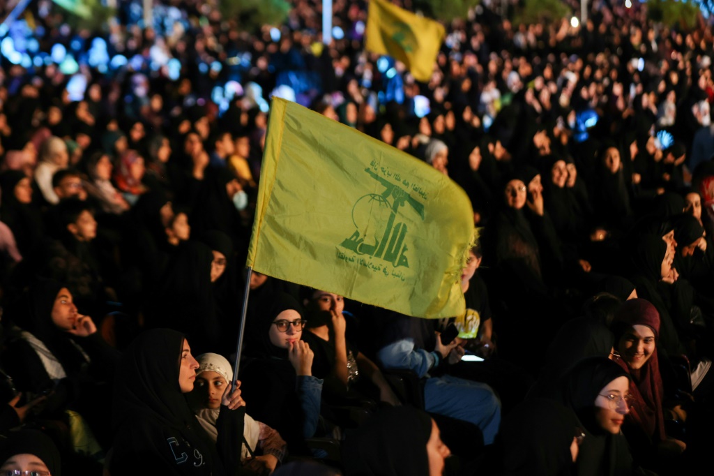 أنصار حزب الله يحملون هواتفهم ويلوحون بعلم الحزب خلال احتفال بمناسبة الذكرى الأربعين لتأسيسه في الضاحية الجنوبية لبيروت في 22 آب/أغسطس 2022 (ا ف ب)