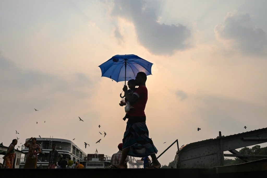     رجل يحمل ابنه تحت مظلة اتقاء من الحر في يانغون ببورما (ا ف ب)