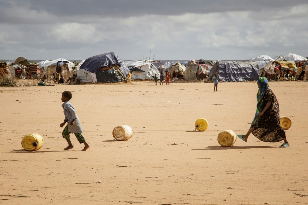     أطفال لاجئون صوماليون يقومون بلف حاويات المياه أثناء إعادتهم إلى مأواهم المؤقت في مخيم داداب للاجئين (أ ف ب)