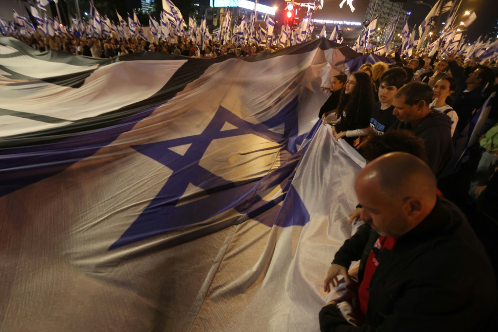 متظاهرون يرفعون علما إسرائيليا كبيرا خلال احتجاج على إصلاح النظام القضائي، في تل أبيب في 29 نيسانأبريل 2023 (ا ف ب)