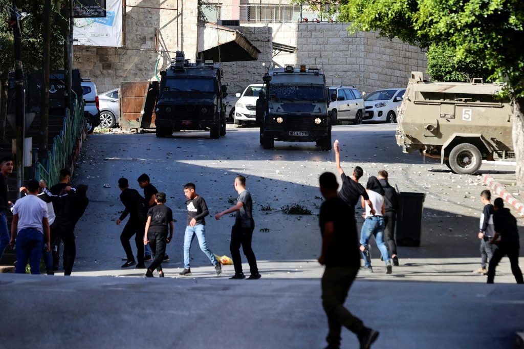 فلسطينيون يرشقون جنودا إسرائيليين بالحجارة في نابلس في الضفة الغربية المحتلة في الرابع من ايار/مايو 2023 (ا ف ب)