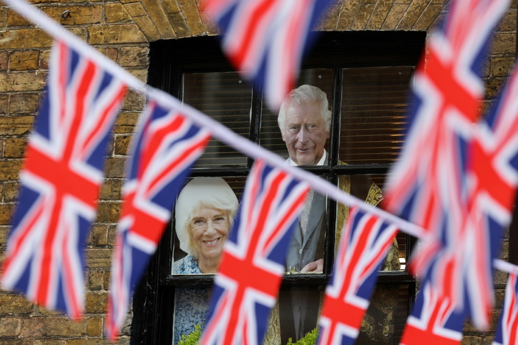 صور الملك تشارلز وزوجته كاميلا على نافذة حانة في شارع ترتفع فيه الأعلام البريطانية، في ويندسور في 2 أيار/مايو 2023 (ا ف ب)
