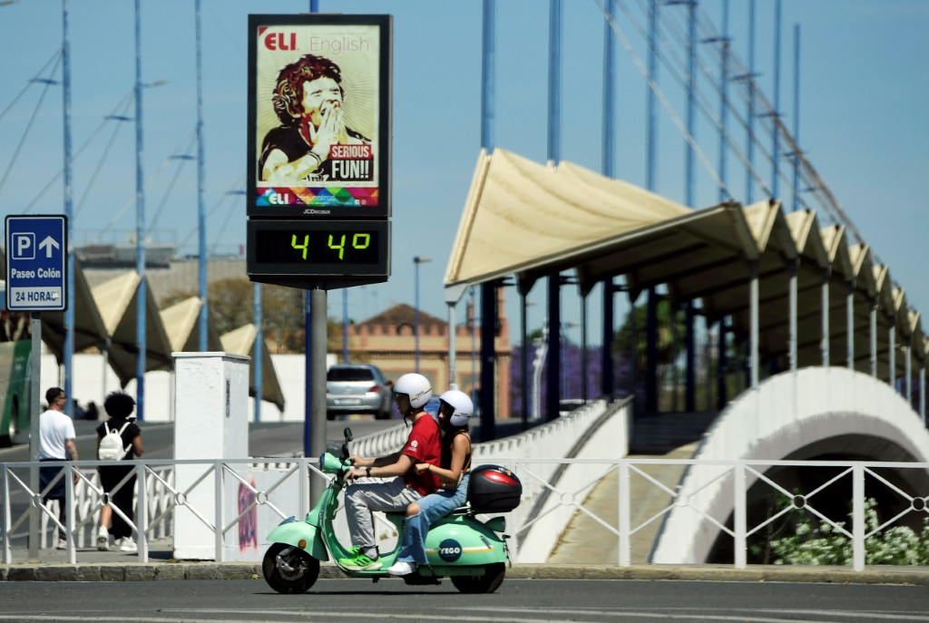 صورة مؤرخة في 26 نيسان/أبريل 2023 لمدينة إشبيلية الإسبانية لشخصين على دراجة نارية أمام مقياس حرارة يظهرها 44 درجة مئوية (ا ف ب)   