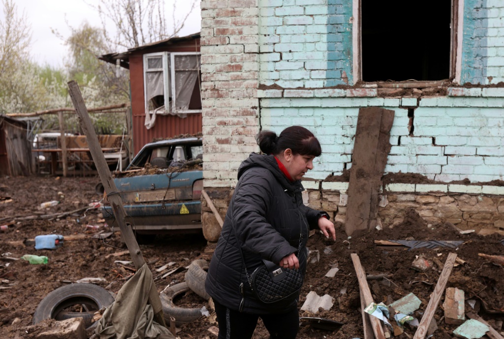     إحدى سكان كوستيانتينيفكا بجوار منزلها الذي دمره الصاروخ (ا ف ب)   