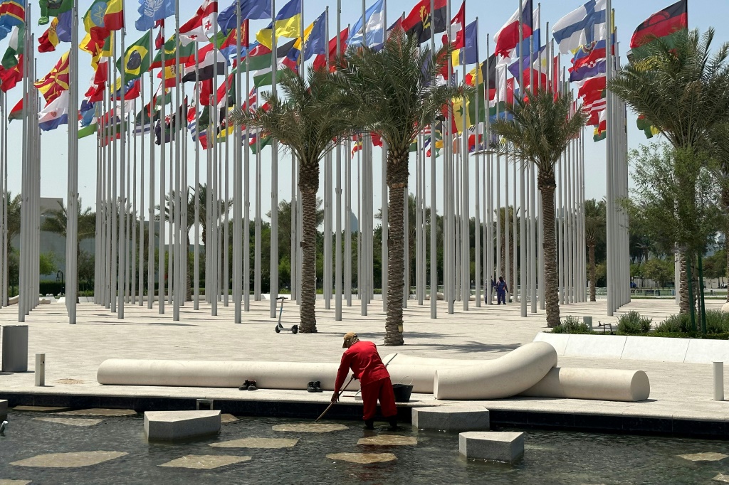 عامل ينظّف بركة مياه بجوار منشأة عامة في الدوحة في 10 أيار/مايو 2023، حيث يُعقد المؤتمر الدولي للإجهاد الحراري المهني في قطر (ا ف ب)