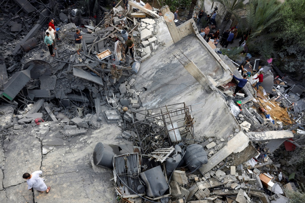 فلسطينيون يتفقدون حطام أحد المباني بعد غارة جوية إسرائيلية على بيت لاهيا شمال قطاع غزة في 11 مايو 2023 (أ ف ب)