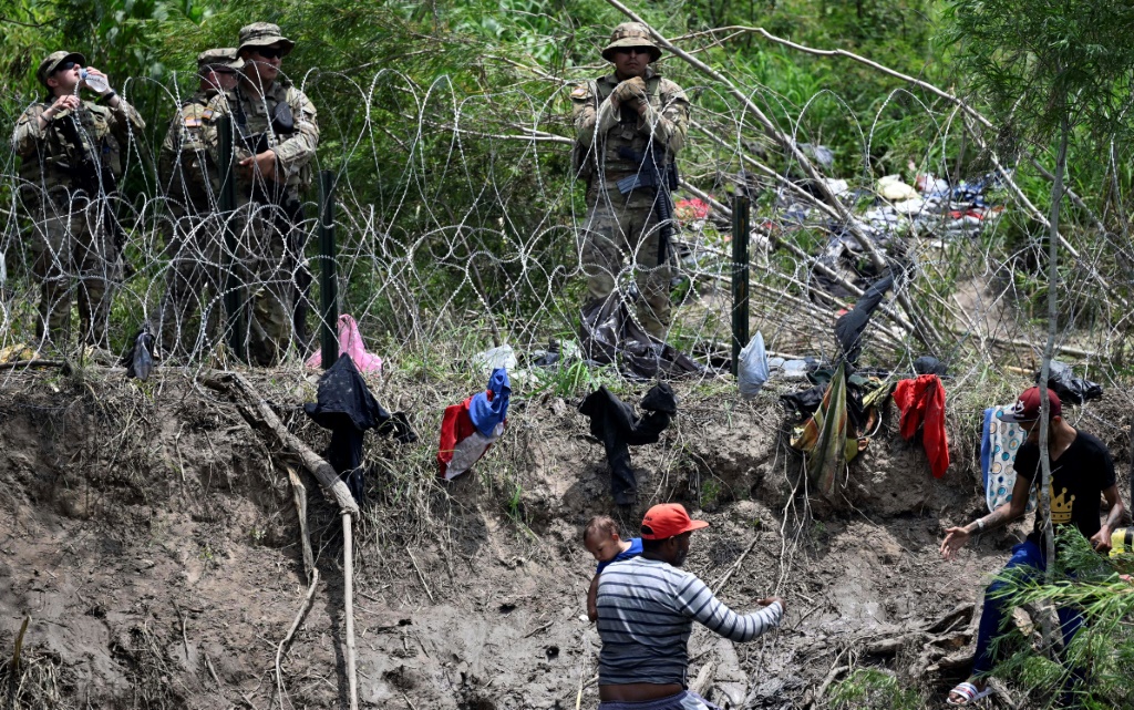 لاجئون عبروا نه غراند ريو الذي يشكل الحدود بين المكسيك والولايات المتحدة، في مواجهة الحرس الوطني الأميركي في 11 أيار/مايو 2023 في براونسفيل بزلاية تكساس الأميركية (ا ف ب)