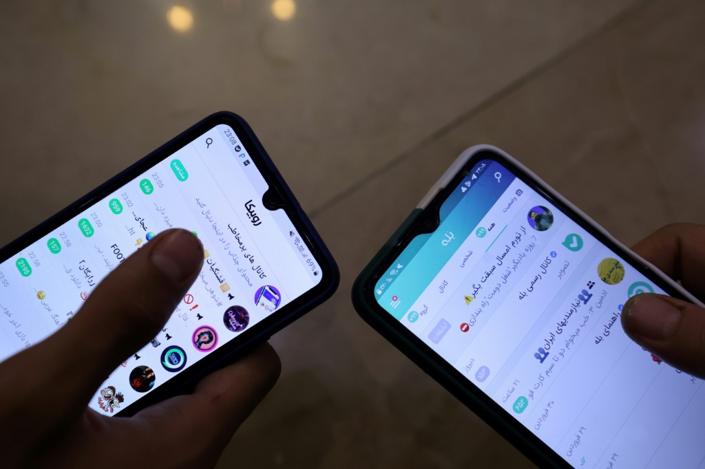 شخصان ينزلان تطبيق "بله" الإيراني للتراسل على هاتفيهما في 19 نيسان/أبريل 2023 في طهران (ا ف ب)