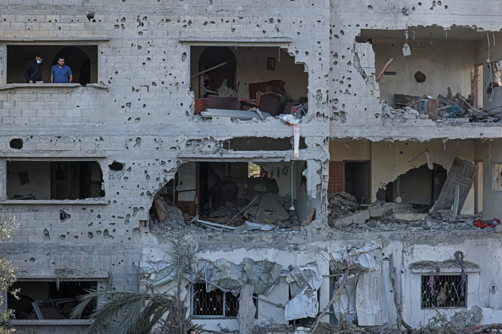    فلسطينيون يتفقدون منازل مدمرة في دير البلح (أ ف ب)