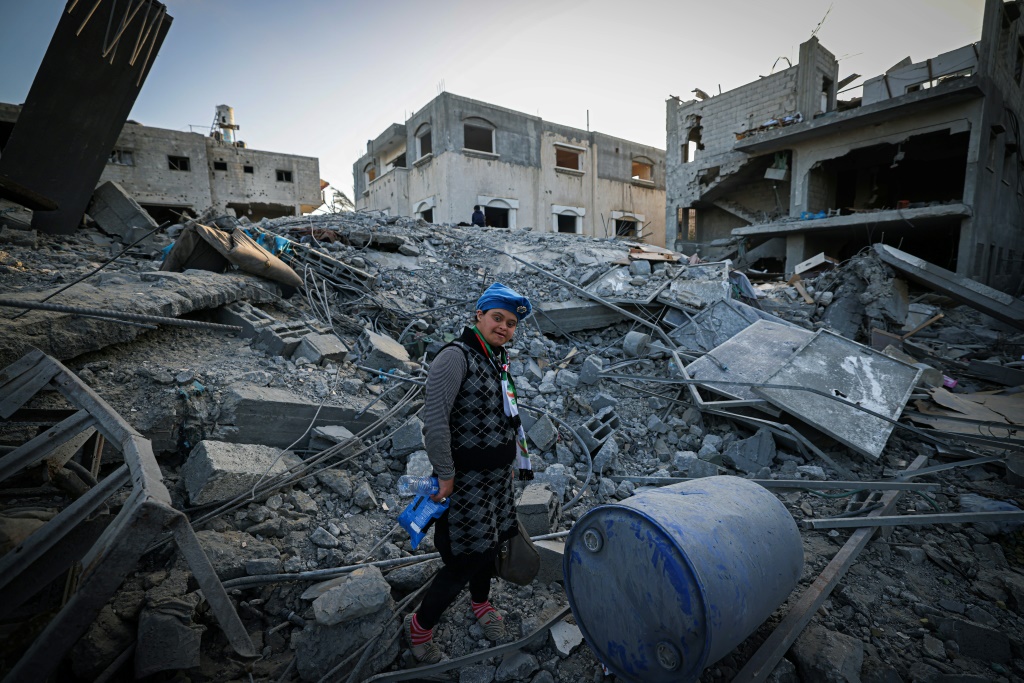    فتاة فلسطينية تمشي وسط أنقاض مبنى سكني مدمر في دير البلح (أ ف ب)   