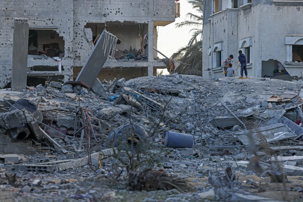    فلسطينيون يتفقدون حطام مبنى سكني بالأرض جراء غارة جوية إسرائيلية على دير البلح وسط قطاع غزة (أ ف ب)