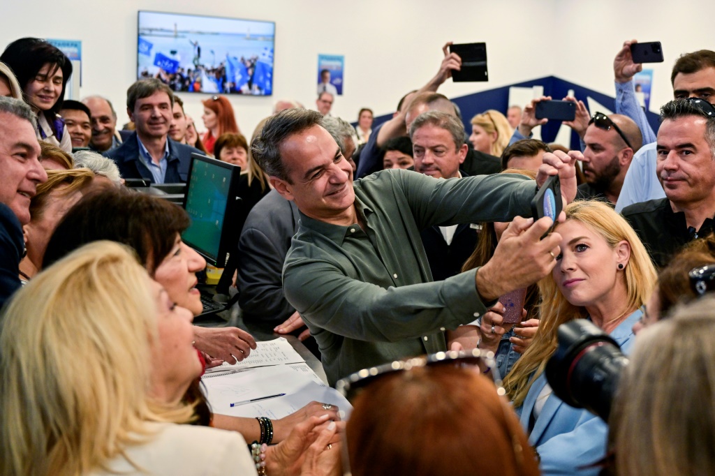 رئيس الوزراء اليوناني كيرياكوس ميتسوتاكيس يلتقط صورة سلفي مع مؤيديه خلال زيارة الى مكتب لحملة حزبه الانتخابية في اثينا في 14 ايار/مايو 2023 (ا ف ب)