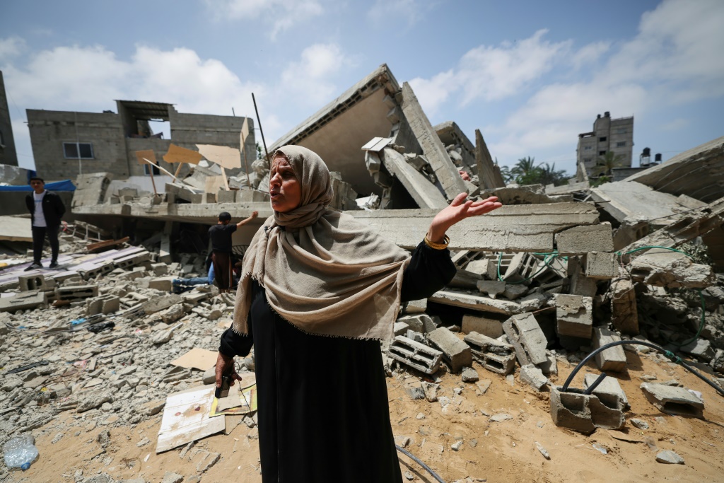 صورة التقطت في 15 أيا/مايو 2023 في بيت لاهيا وتظهر فيها الفلسطينية نجاح نبهان (56 عاما) وهي تتحدث وتشير إلى أنقاض المبنى السكني الذي كانت تقطنه هي وعائلتها قبل أن تقصفه إسرائيل (ا ف ب)