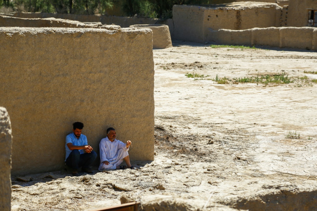  رجلان يجلسان قرب منزل مهجور في البو زياد في محافظة الديوانية في جنوب العراق في 17 نيسان/أبريل 2023 (أ ف ب)