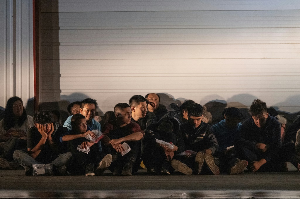    المهاجرون ينتظرون حافلة لنقلهم إلى مركز معالجة بعد أن سلموا أنفسهم إلى وكلاء حرس الحدود الأمريكي بعد عبورهم من المكسيك في فرونتون ، تكساس (أ ف ب)