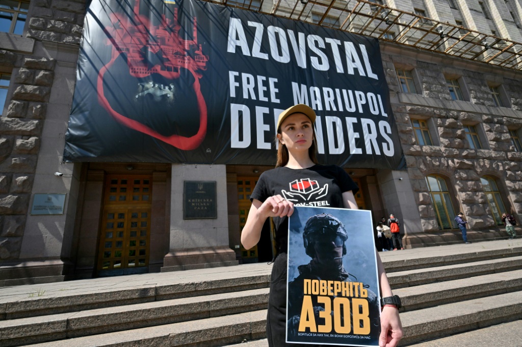     زوجة جندي أسره الروس في مصنع آزوفستال في ماريوبول، تحمل لافتة كتب عليها "عودة آزوف" أثناء اعتصام في العاصمة الأوكرانية كييف في 11 أيار/مايو 2023 (أ ف ب)