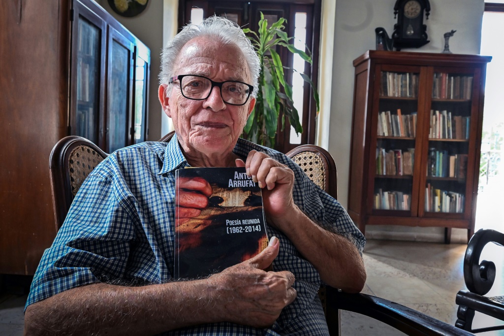 الكاتب المسرحي الكوبي أنتون أروفات يحمل أحد مؤلفات خلال مقابلة مع وكالة فرانس برس داخل منزله في هافانا بتاريخ 15 أيلول/سبتمبر 2022 (ا ف ب)