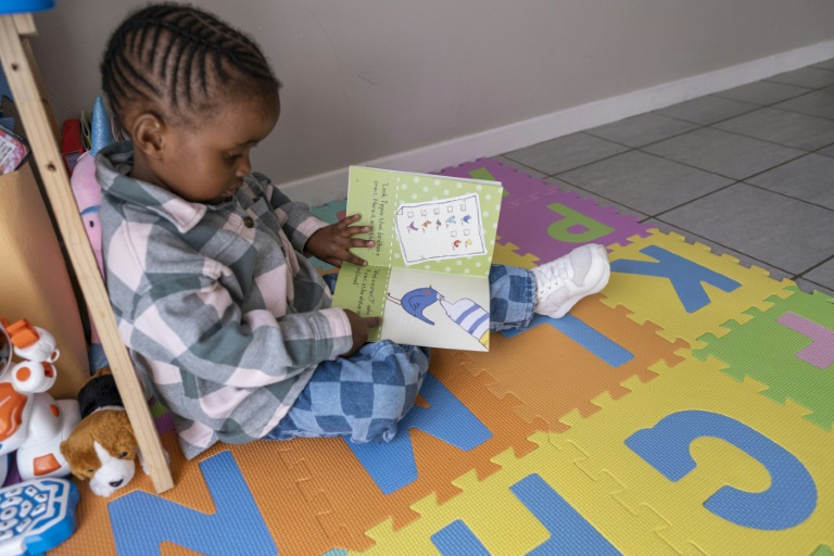 الطفلة ليثوكوثولا بينغو تقرأ كتاباً في منزلها في جوهانسبرغ بتاريخ 13 أيار/مايو 2023 (أ ف ب)