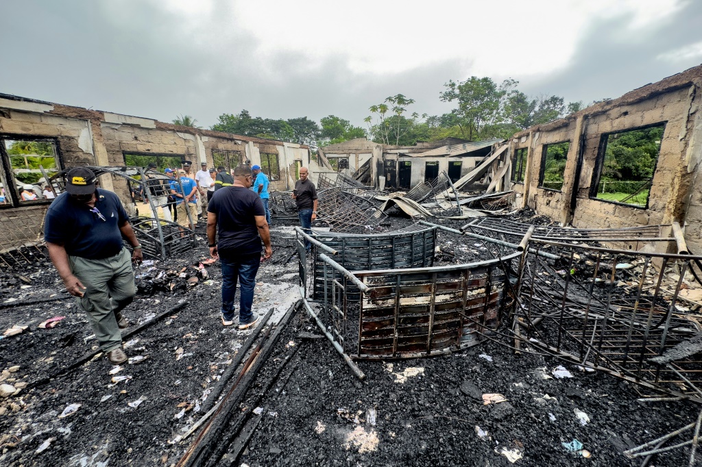 محققون في مهجع للإناث في مدينة المهدية في وسط غوايانا في 22 أيار/مايو 2023 بعدما أتى عليه حريق أوقع 19 قتيلاً، جميعهم قاصرون (ا ف ب)