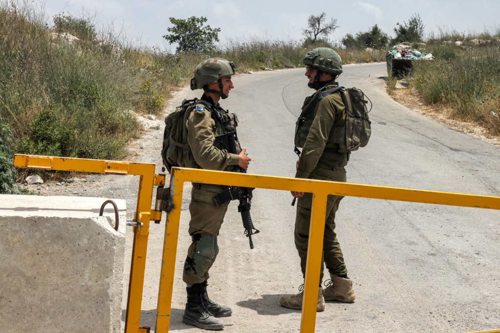    جنديان اسرائيليان على حاجز قرب بؤرة حوميش الاستيطانية السابقة بالضفة الغربية المحتلة في 29 أيار/مايو 2023 (أ ف ب)