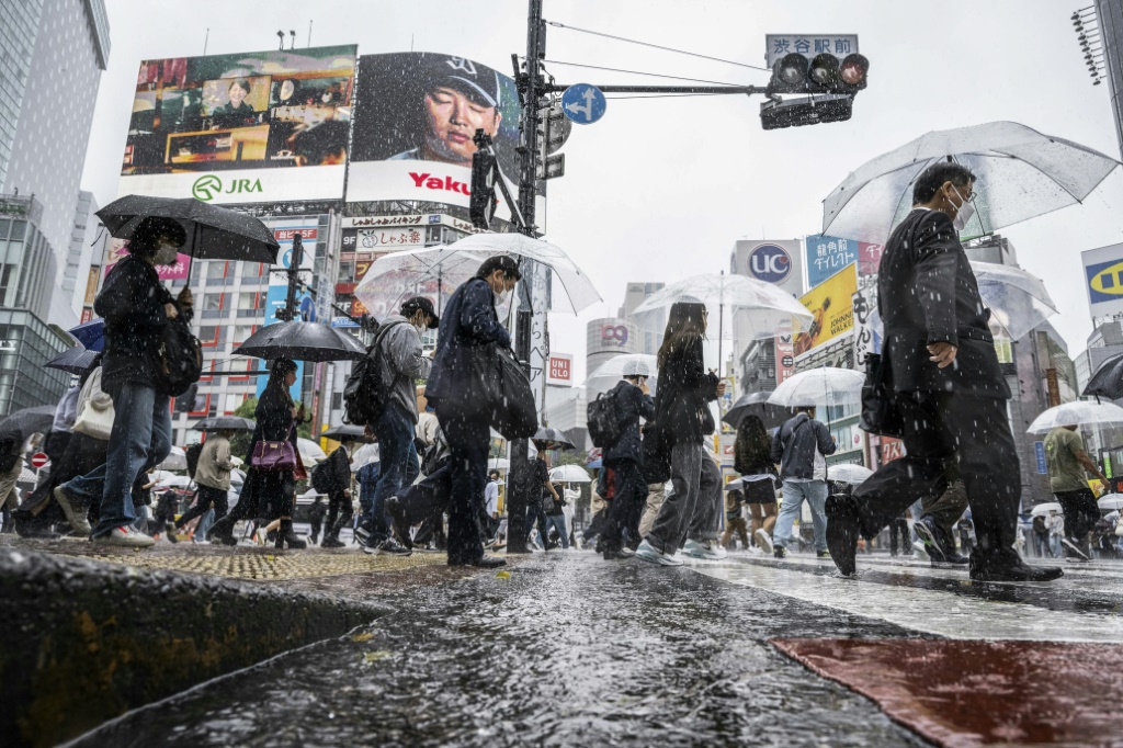     مارة يحملون مظلاتهم تحت المطر الغزير في منطقة شيبويا في طوكيو في 2 حزيران/يونيو. (أ ف ب)   