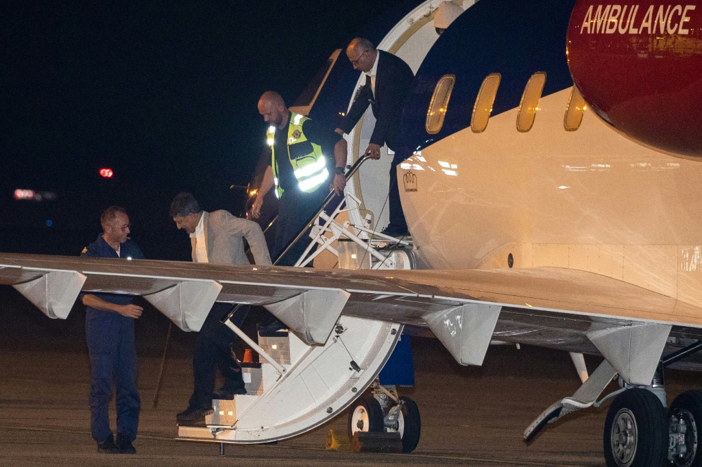    المواطنان النمساويان الإيرانيان مسعود مصاحب (الثاني إلى اليسار) وكمران غديري ينزلان من الطائرة عند وصولهما إلى مطار ميلسبروك العسكري في بلجيكا بعد إطلاق سراحهما من إيران. (ا ف ب)